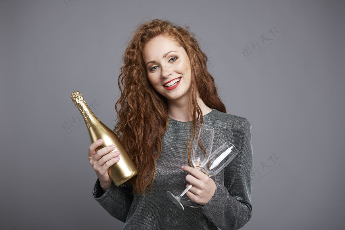 欢快微笑的女人拿着一瓶香槟和香槟笛快乐乐趣夜晚