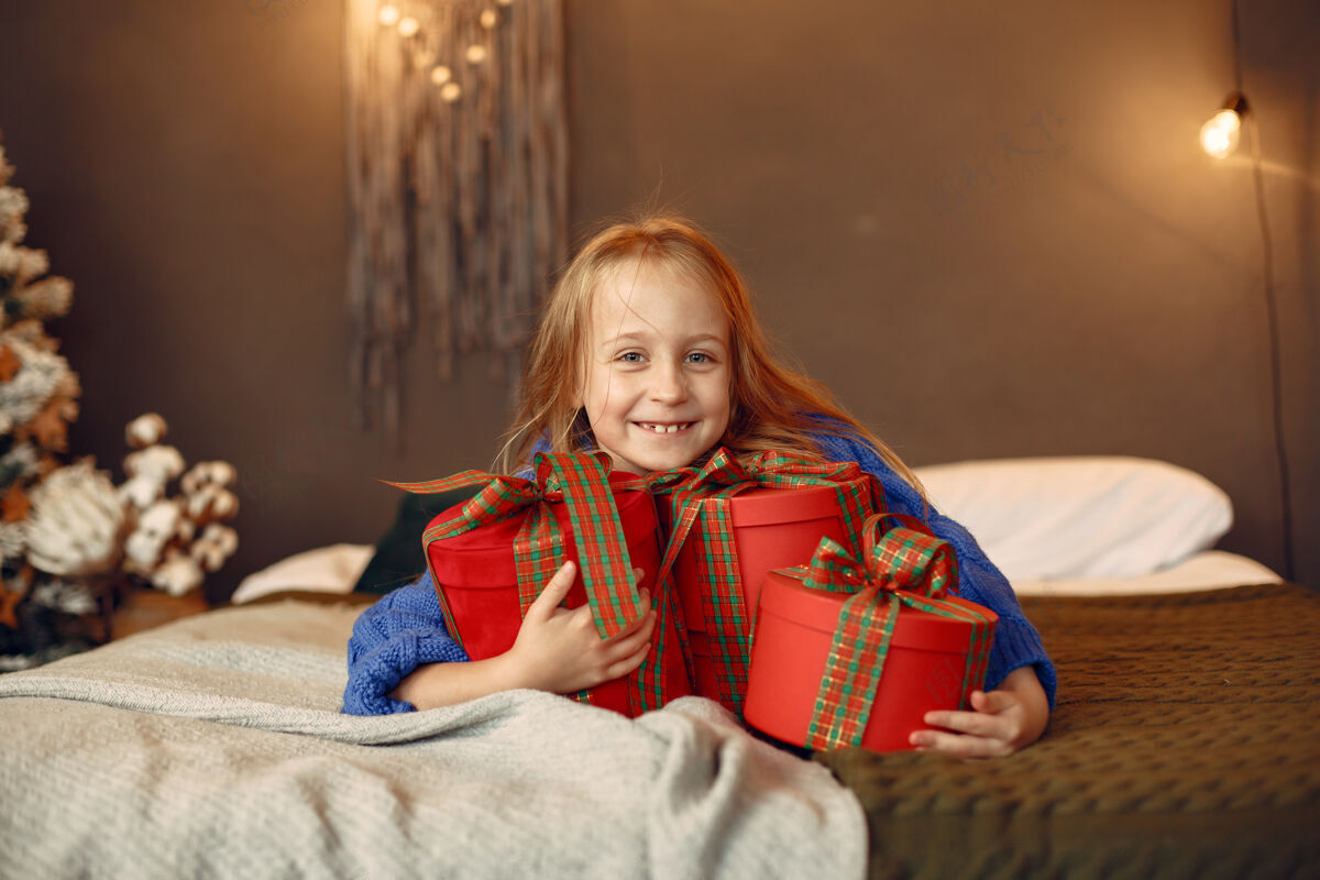 室内穿蓝色毛衣的孩子坐在圣诞树旁的女儿庆祝女儿玩具