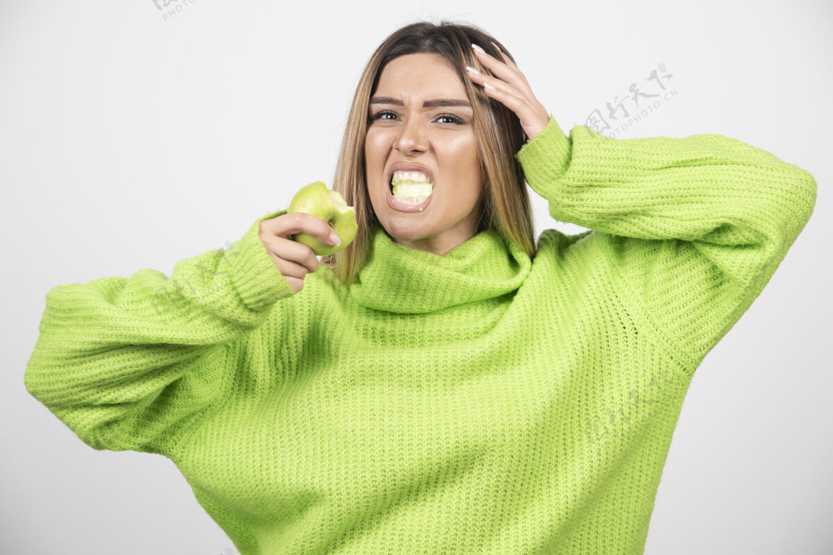 肖像穿着绿色t恤的年轻女子正在吃苹果水果吃营养