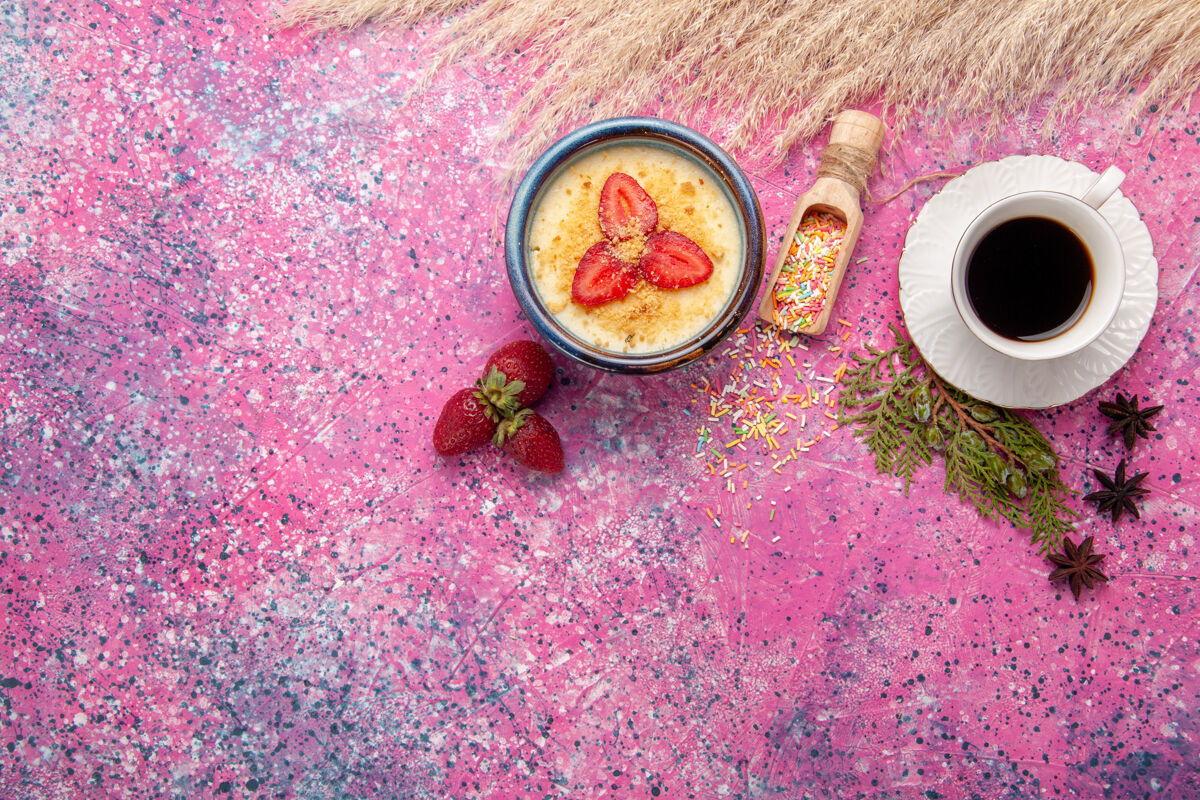 生的俯瞰美味的奶油甜点与红色切片草莓和茶杯浅粉色背景甜点冰淇淋浆果奶油甜水果杯子茶花