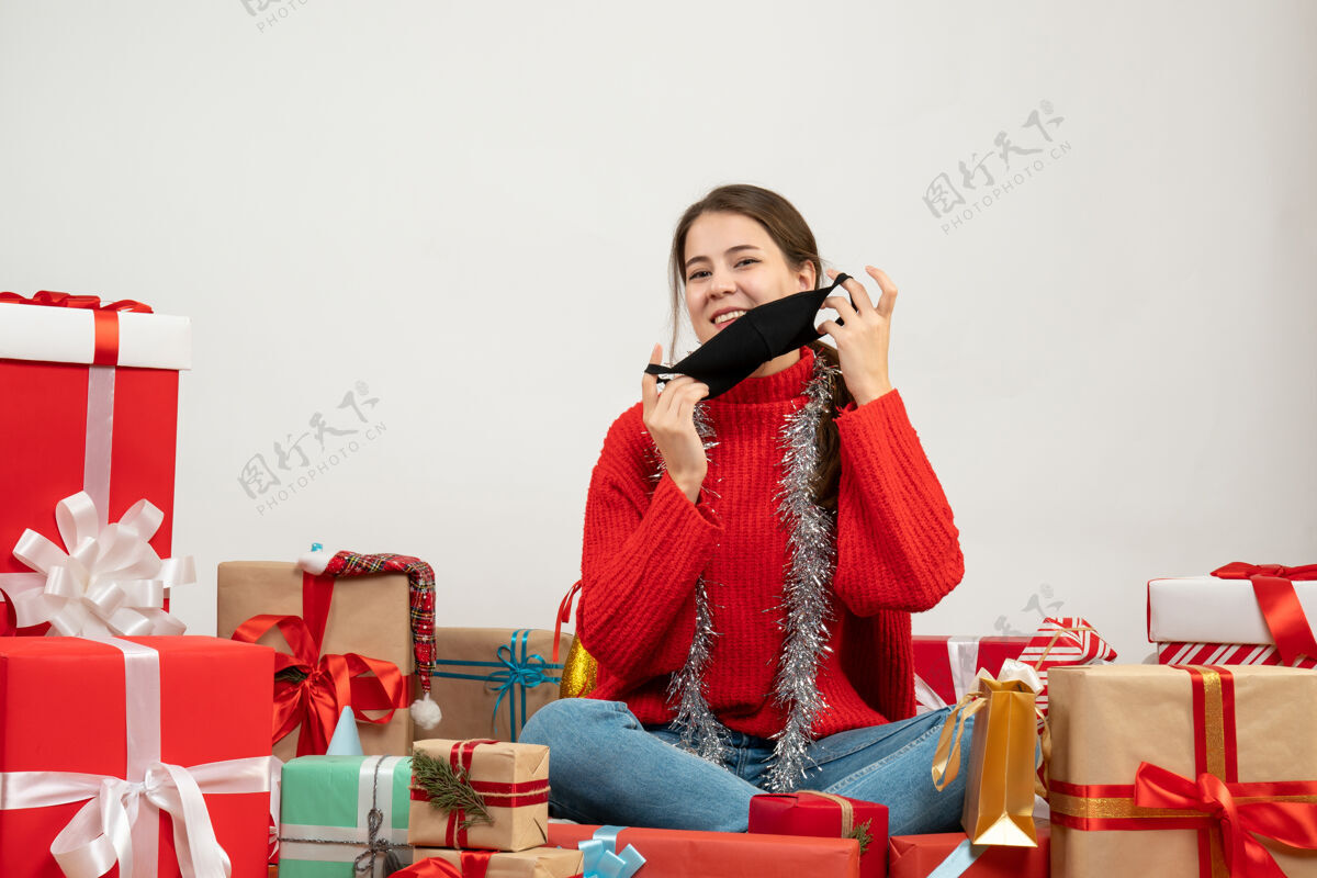 年轻女孩穿着红色毛衣的年轻女孩摘下面具围坐在白色的礼物旁边礼物红色采取