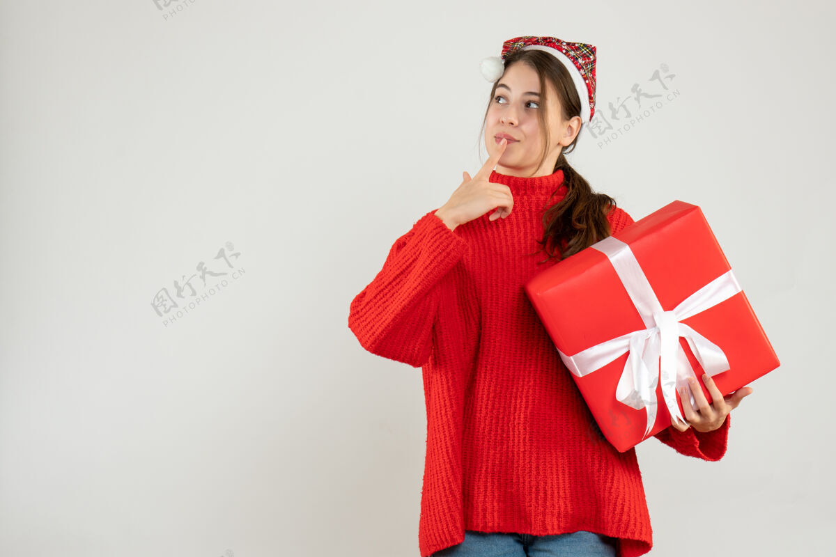 礼物一个戴着圣诞帽 拿着礼物的女孩购物者思考圣诞老人