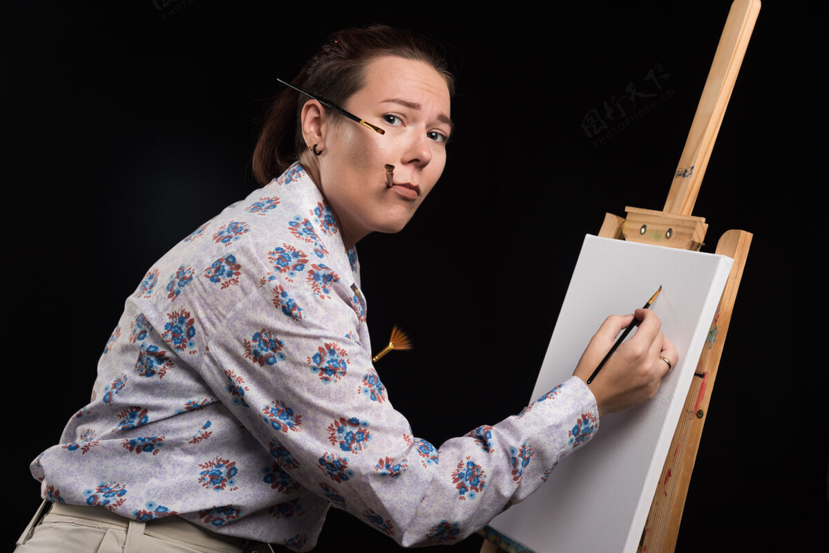 铅笔女画家用铅笔在画布上画一幅画 背景是黑色的艺术家画布绘画