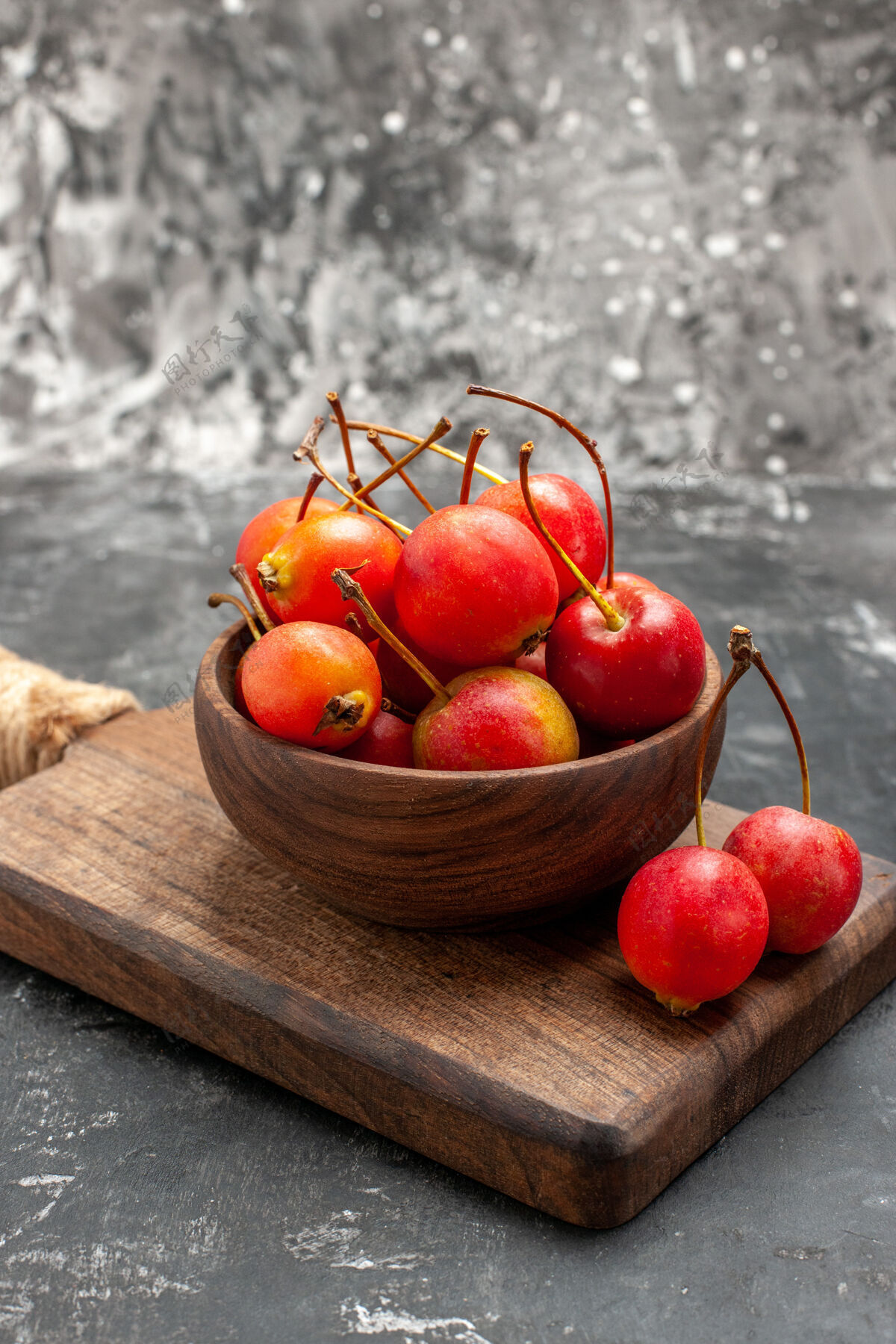 可食用红色的樱桃在棕色的碗和灰色的小砧板上的垂直视图甜浆果多汁