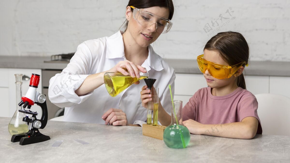 安全小女孩和女老师用显微镜和试管做科学实验孩子科学家试管