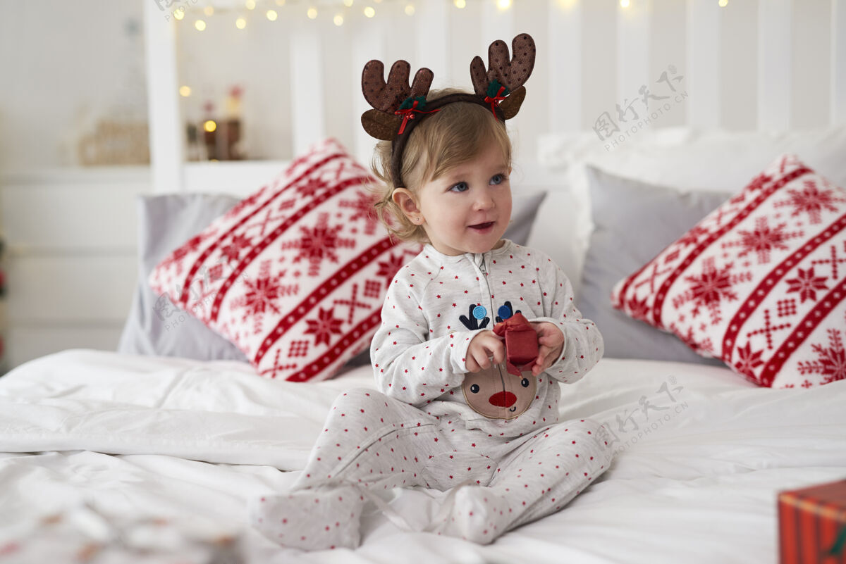 女婴可爱的宝宝在床上打开圣诞礼物圣诞礼物坐室内