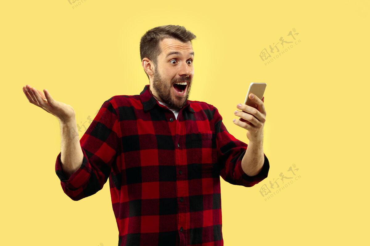智能手机穿着衬衫的年轻人的肖像正面图流行的颜色在智能手机里疯狂的新闻顺序年轻胡须