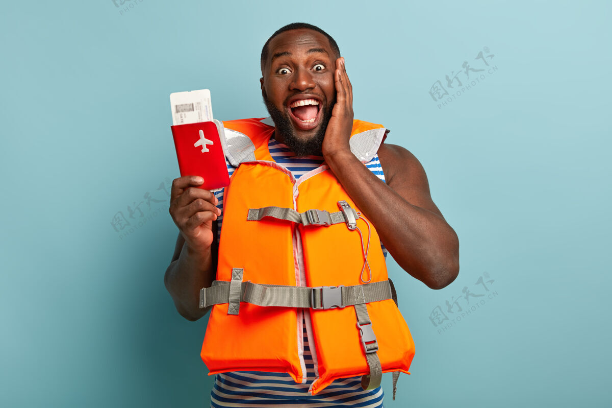 非洲快乐黑人的半身镜头享受即将到来的旅行 手持红色护照和门票 分享印象夹克游泳肌肉