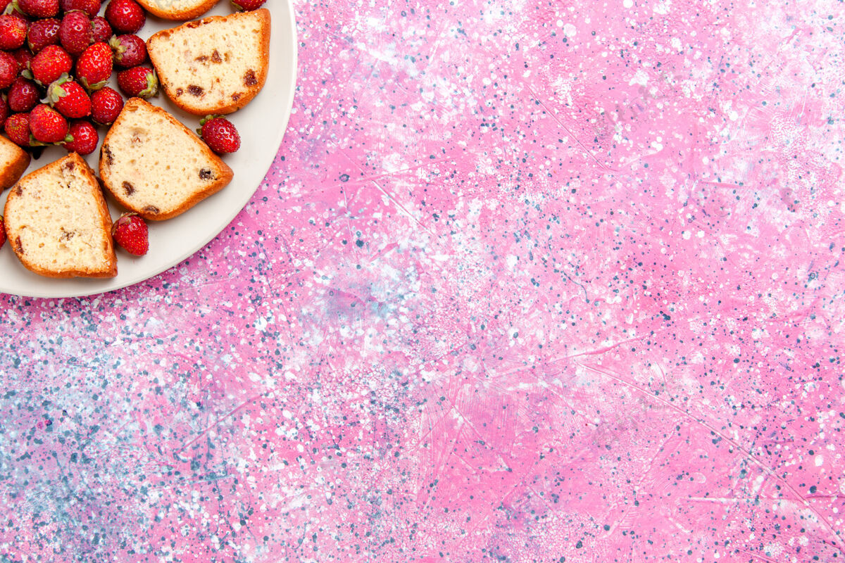 葡萄干顶视图蛋糕片与葡萄干内盘新鲜草莓粉红背景蛋糕烤甜饼干彩色糖饼干颜色烘焙饼干