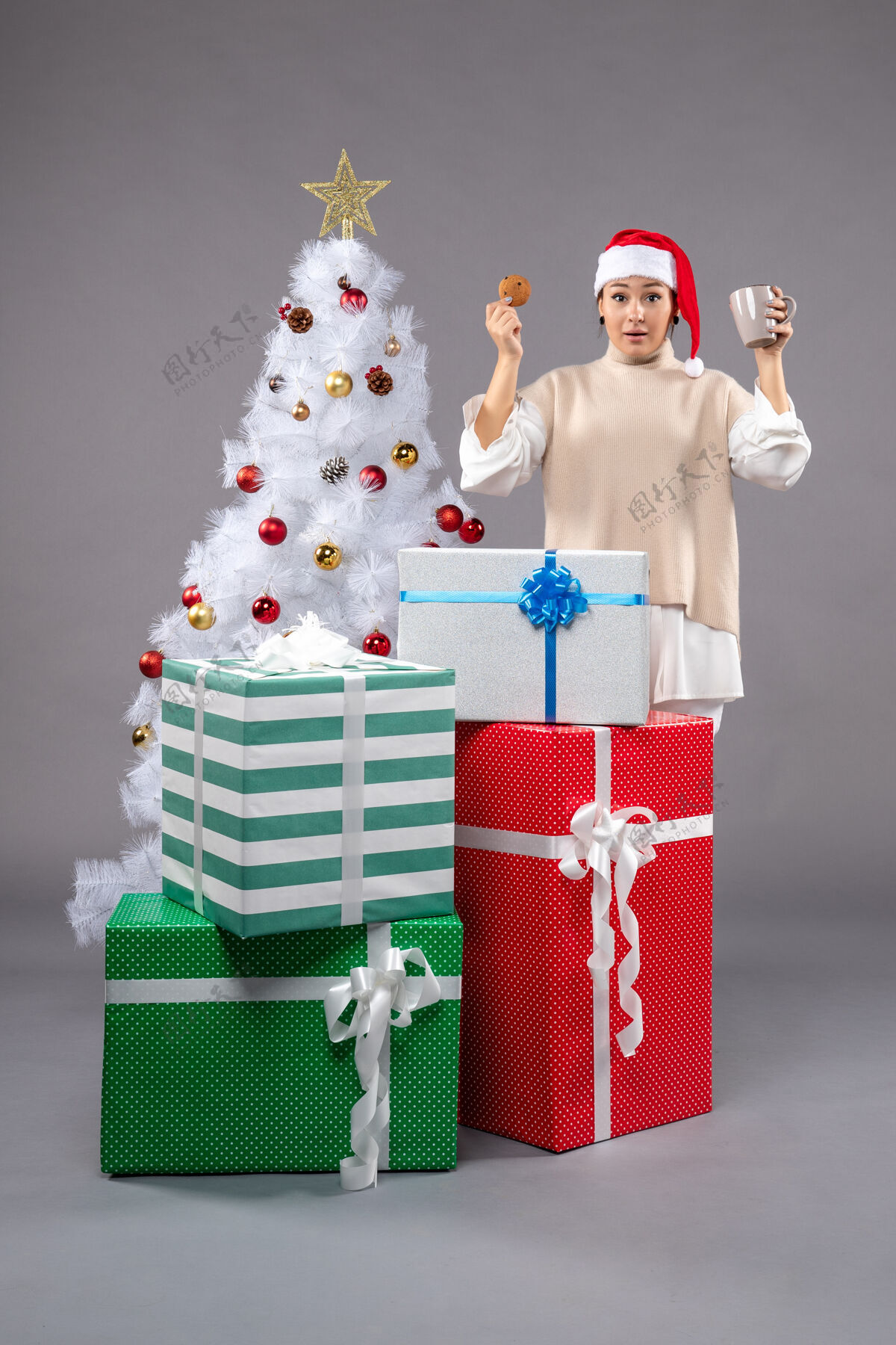 圣诞树年轻的女人喝着茶 灰色的饼干表演者灰色圣诞老人