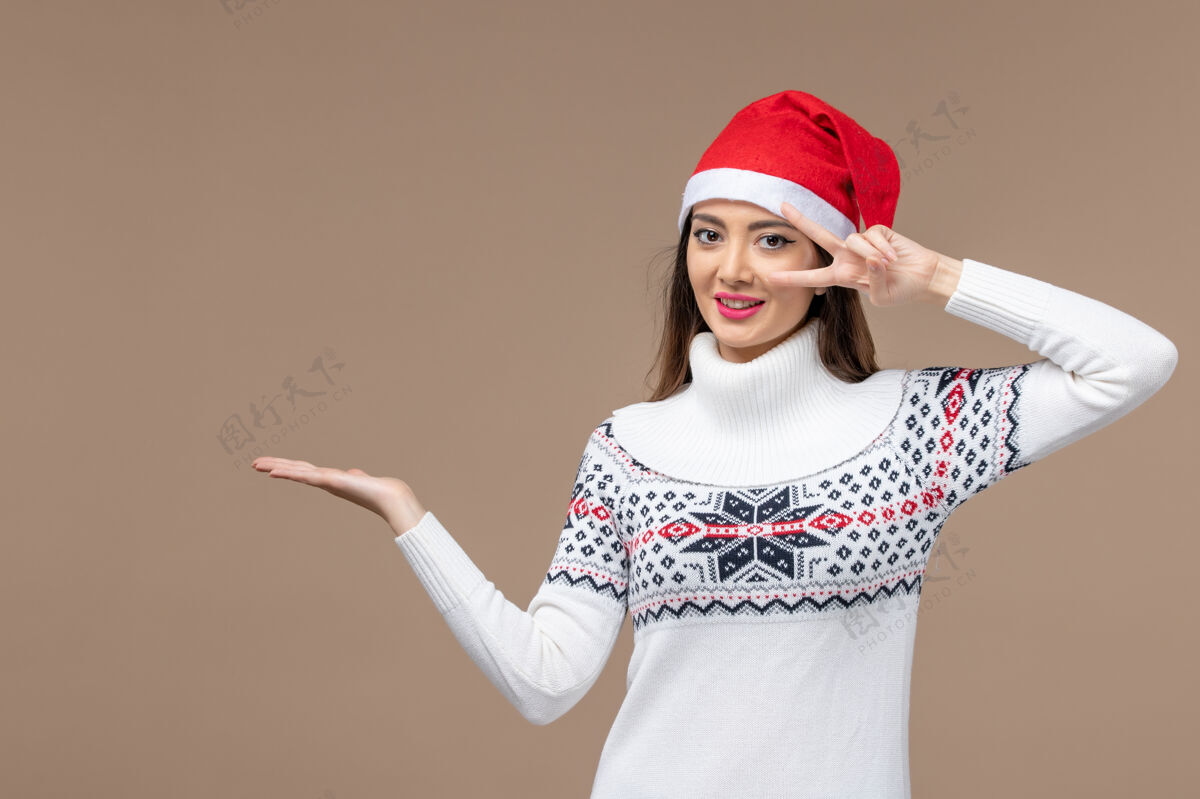 背景正面图：年轻女子在棕色背景上摆姿势庆祝圣诞节可爱时尚休闲