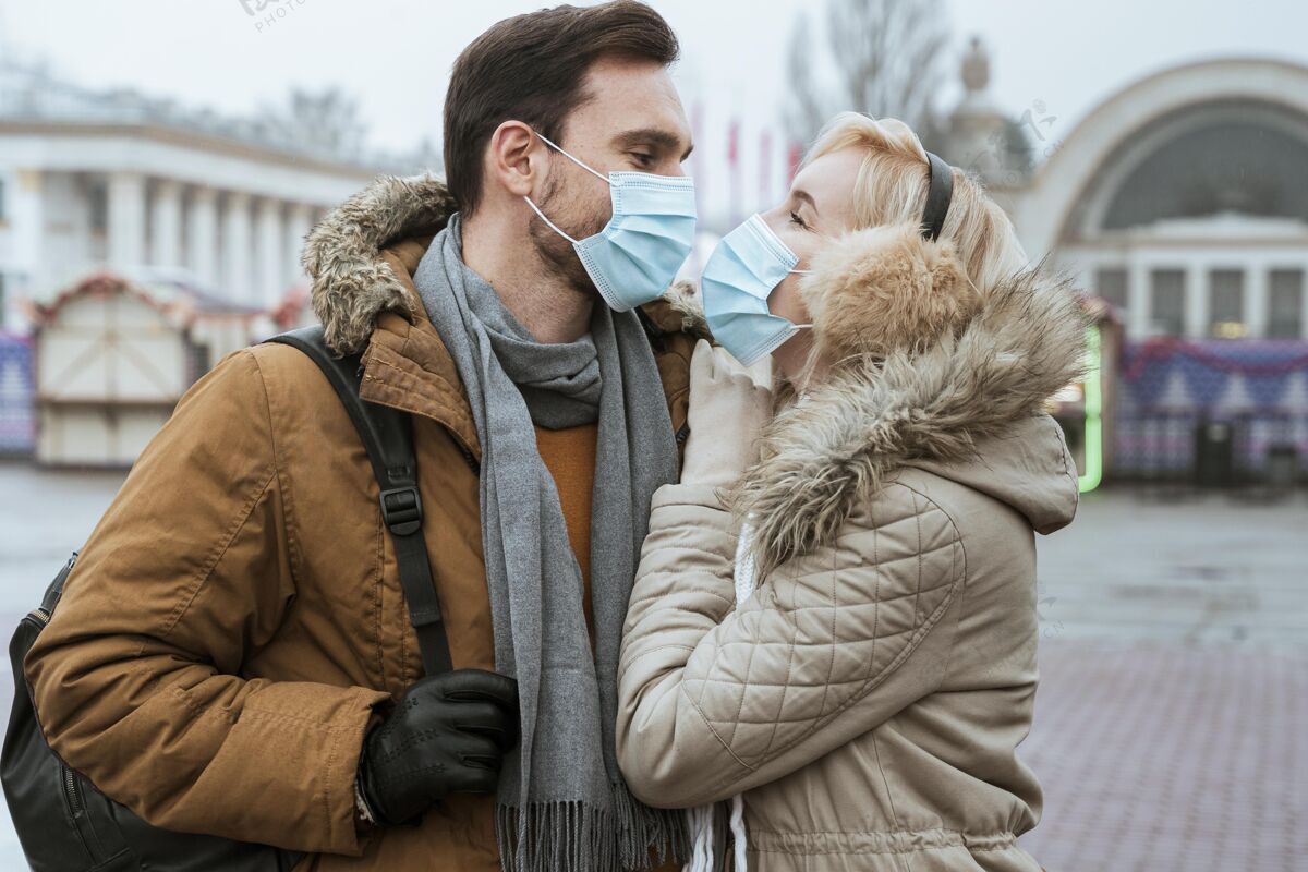 情人冬天的情侣戴着医用口罩拥抱着结合男人城市