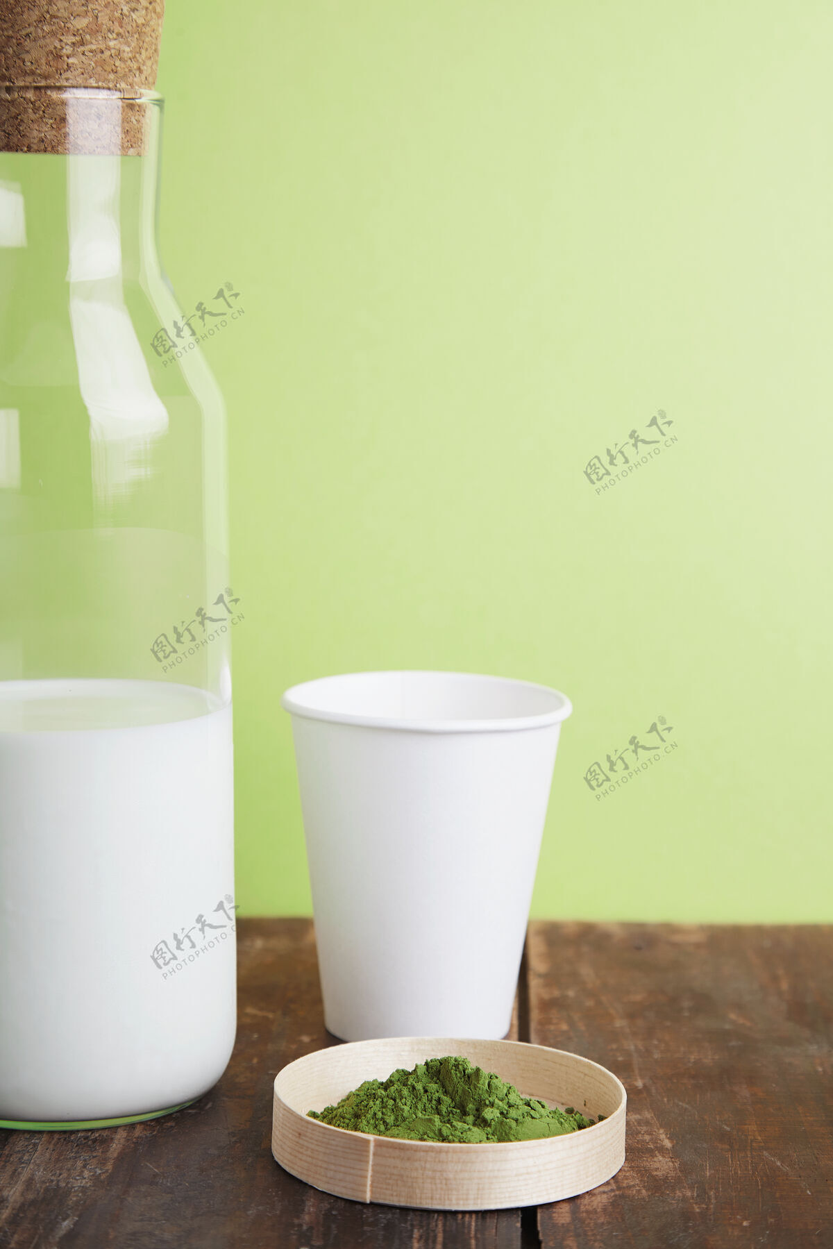 早餐古董奶瓶 白纸外卖玻璃和有机优质抹茶粉放在绿色简单背景前的棕色拉丝木桌上特写健康热木材
