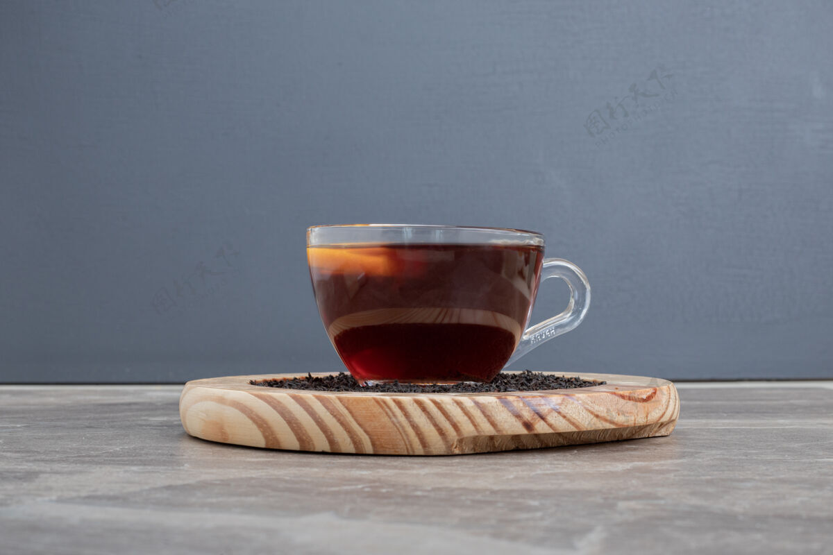 红茶放在大理石桌上的木盘上的热茶木制饮料杯子
