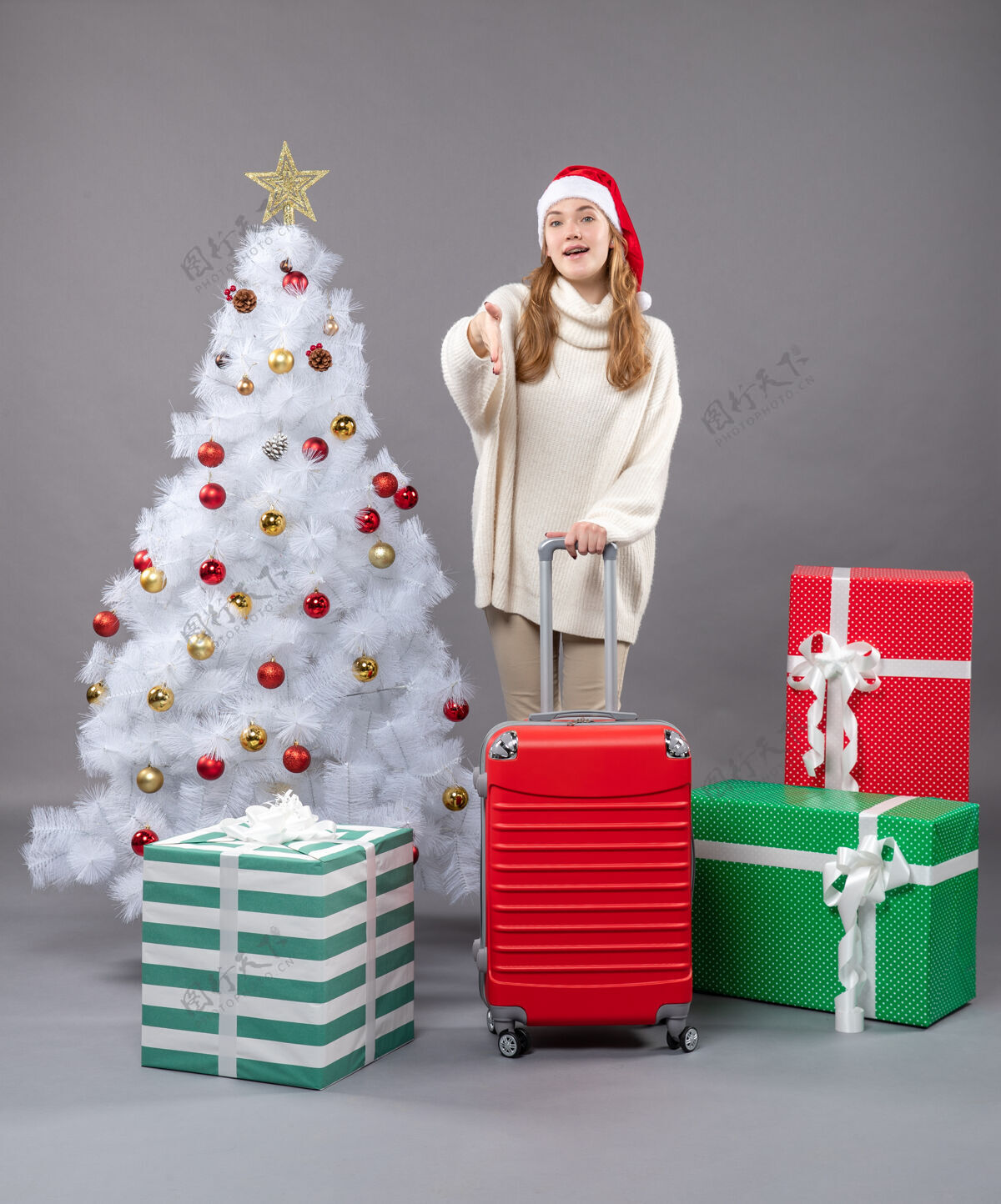 旅行前视图满意的年轻女孩戴着圣诞帽站在圣诞树和礼物附近站立年轻帽子