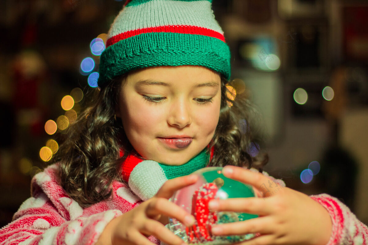 玻璃可爱的女孩抱着她的圣诞玻璃球看黑发年轻人