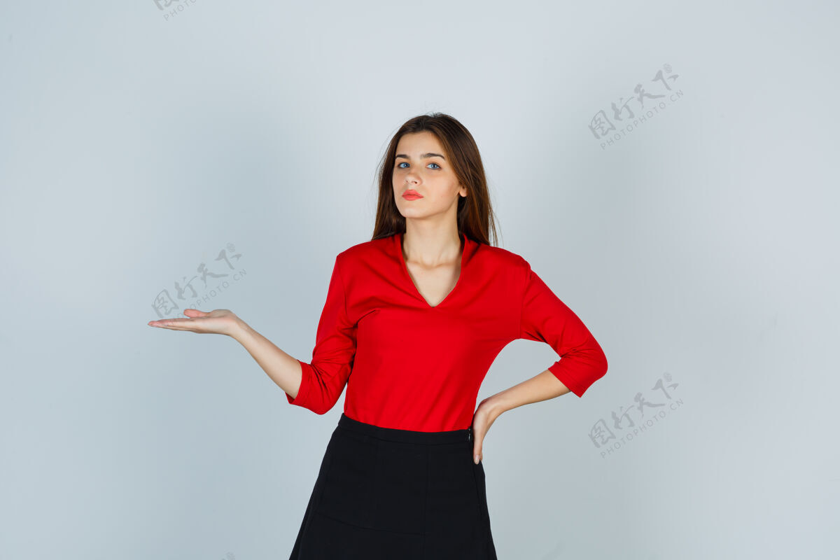 商业穿着红衬衫 裙子的年轻女士假装拿着什么东西 手放在臀部专业抱着假装