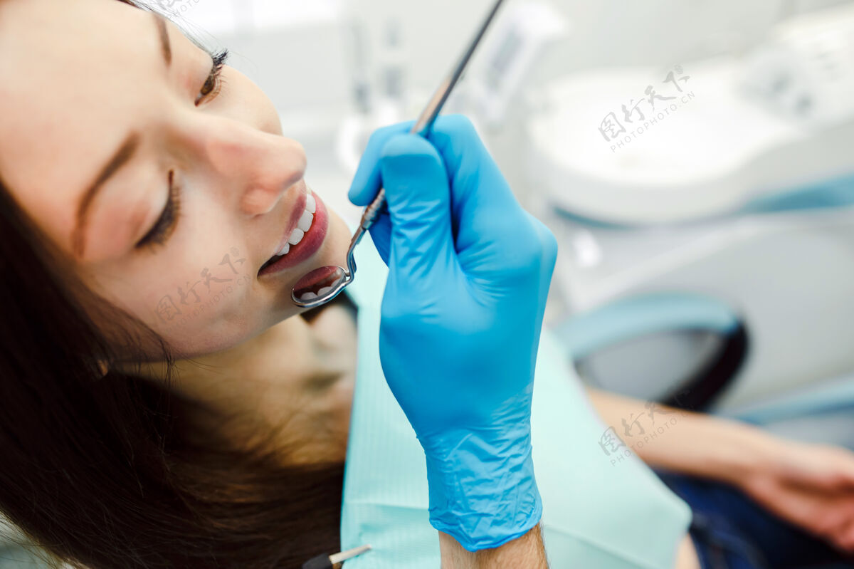 男性用镜子检查女人的牙齿卫生成人牙医