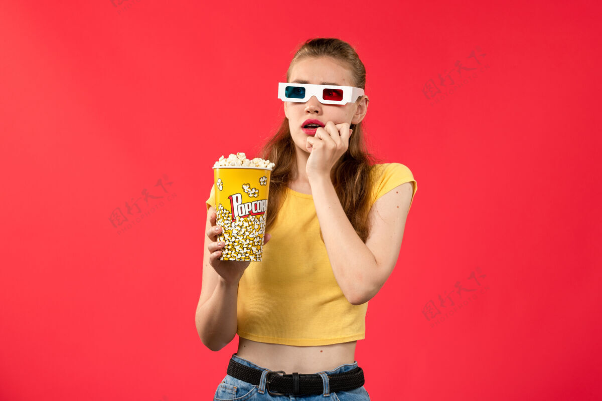 年轻人正面图年轻女性在电影院拿着爆米花在红墙电影院吃零食的女性趣味电影成人电影电影
