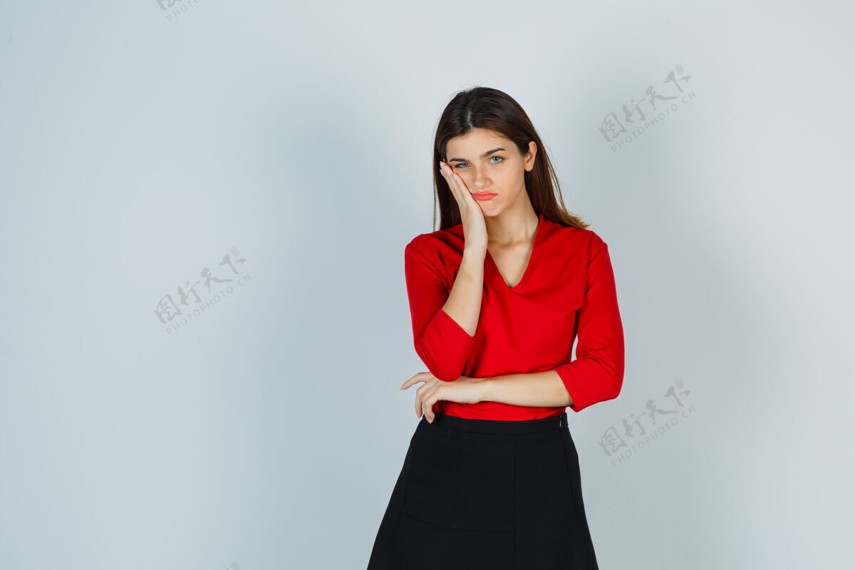 孤独穿着红衬衫的年轻女士 裙子把手放在脸颊上 看上去很忧郁喜怒无常美丽闷闷不乐