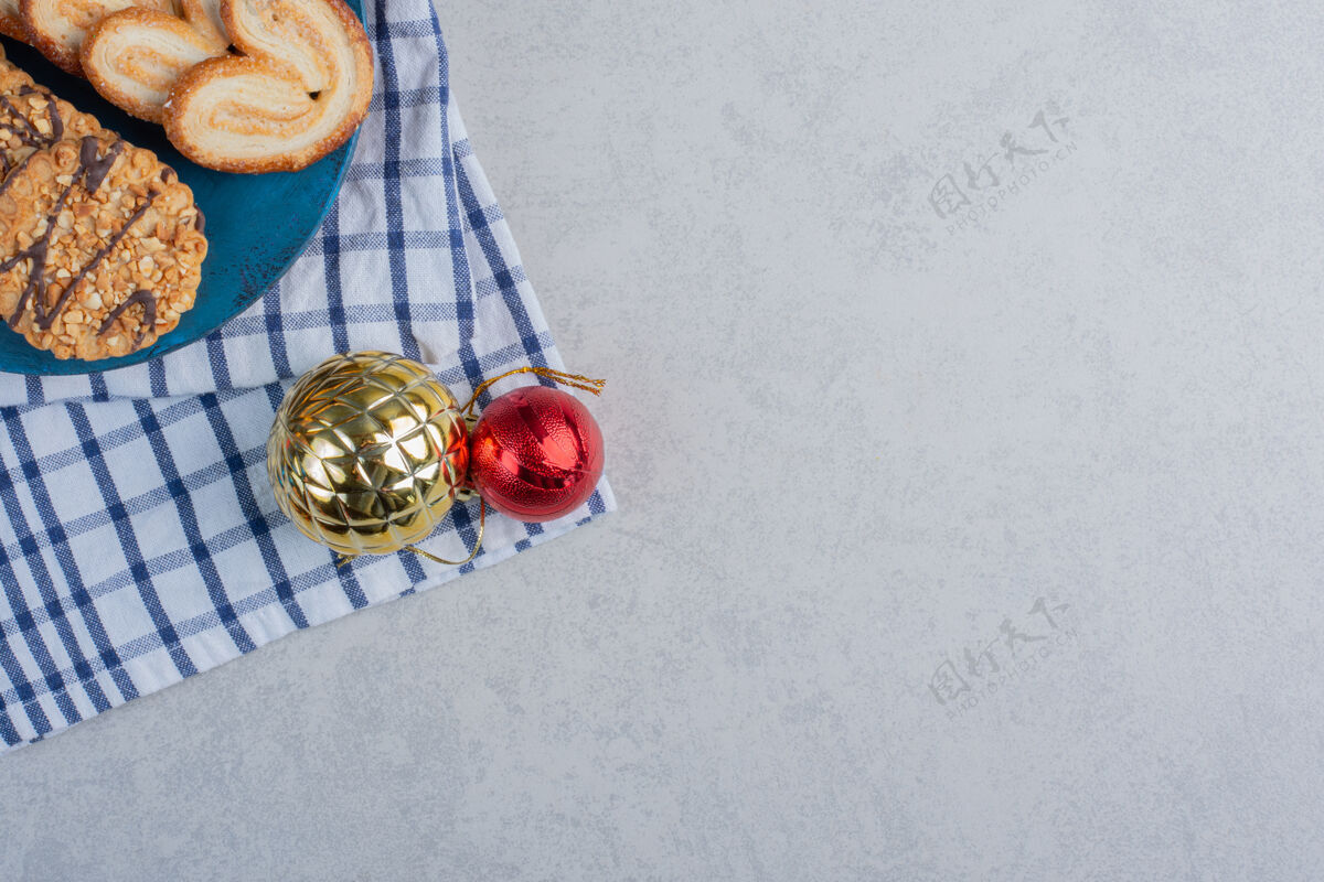 零食蓝色板上的一捆饼干 旁边是大理石表面毛巾上的圣诞饰品毛巾甜点糖果