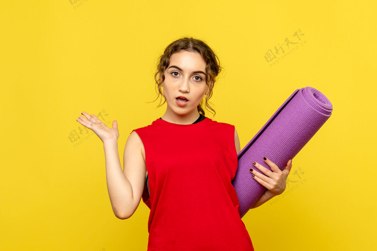 地毯黄色墙壁上有紫色地毯的年轻女子的正视图女性快乐成人