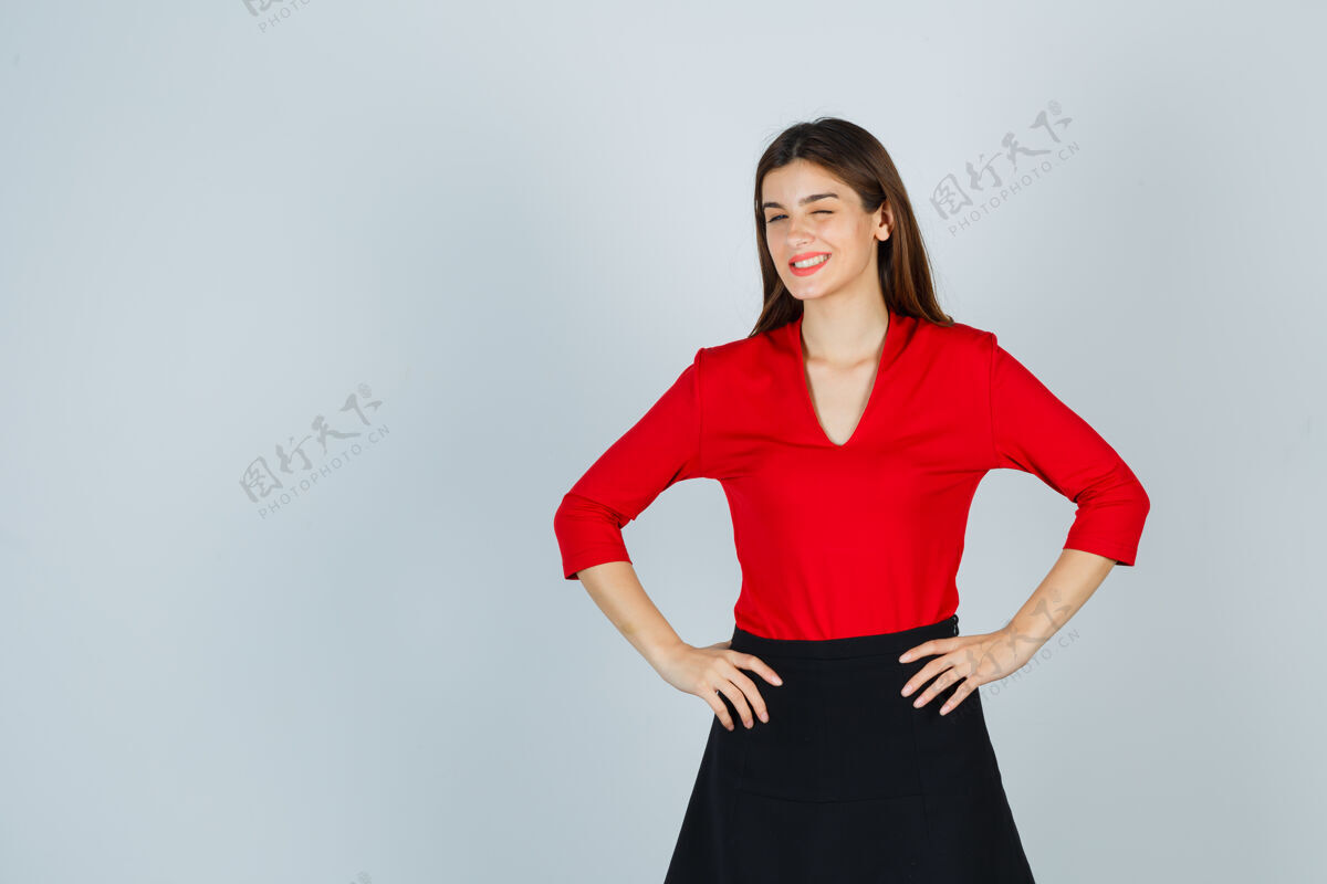 时尚穿红色上衣 黑色裙子的年轻女士双手叉腰 眨着眼睛 看起来很可爱臀部小衬衫