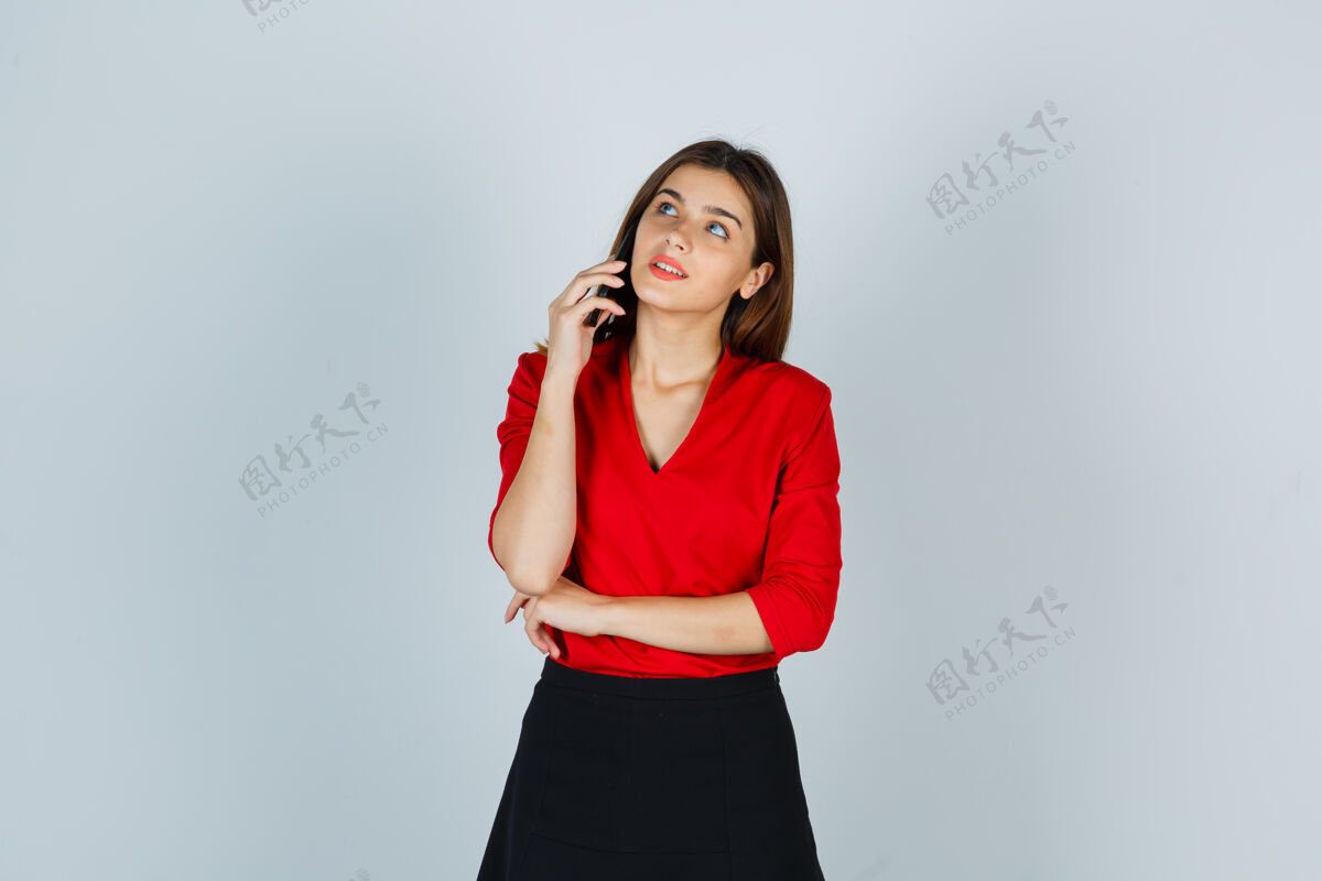 年轻穿红衬衫的年轻女士 穿着裙子讲着手机 看起来很开心美丽肖像漂亮