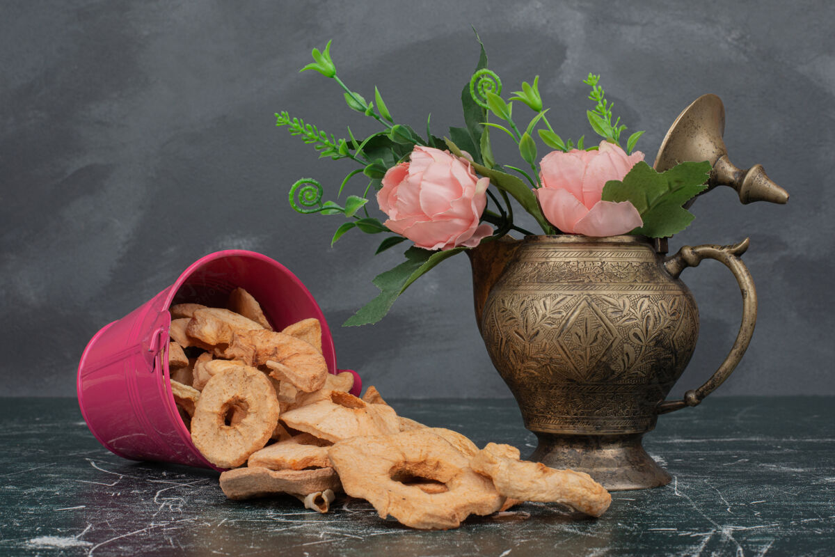 古老的粉红色的桶 放着干苹果和花瓶 放在大理石桌上食物花瓶甜味