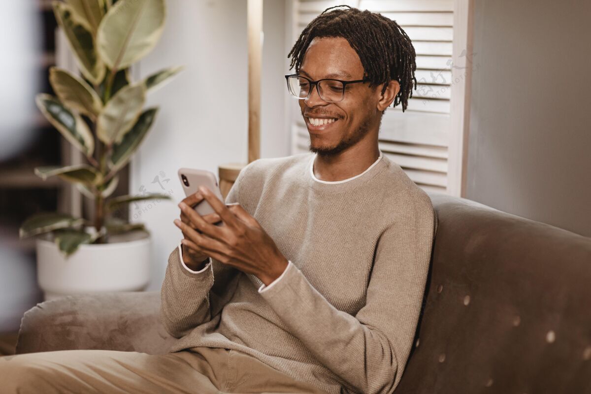 男性在家沙发上使用现代智能手机的男人科技年轻人当代