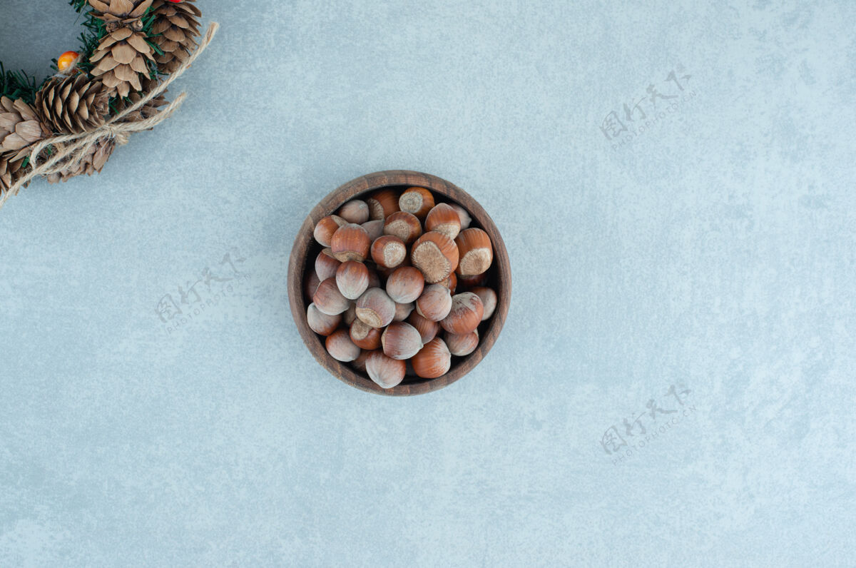 花环松果花环和一碗榛子放在大理石上顶部节日配料