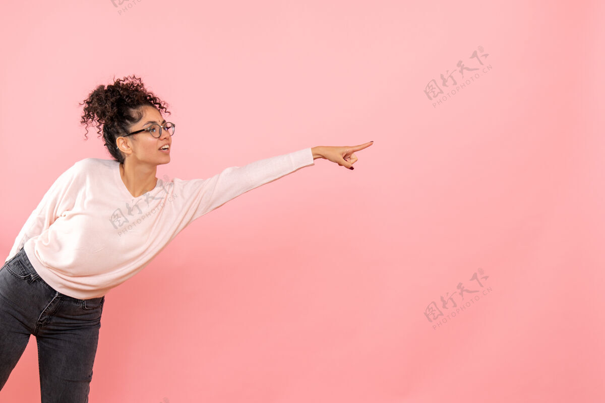 女性年轻女子指着粉色墙壁的正视图年轻女性天空情感