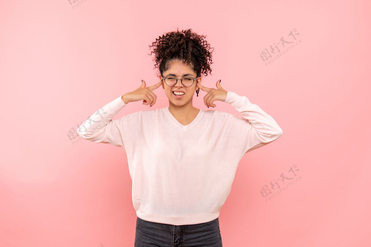 微笑粉红色墙壁上闭着耳朵的漂亮女人的正视图美女快乐成人