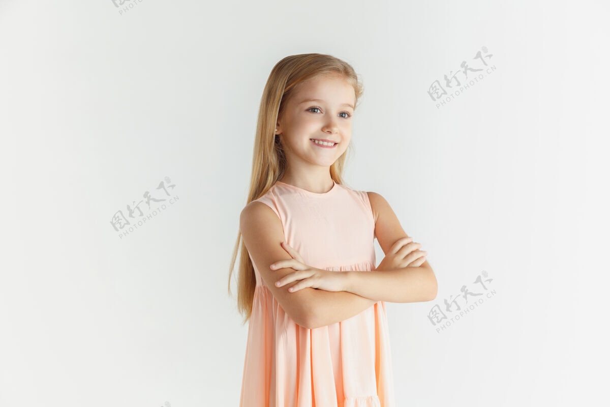 面部时尚的微笑小女孩在白色工作室里穿着隔离的裙子摆姿势自信表情孩子