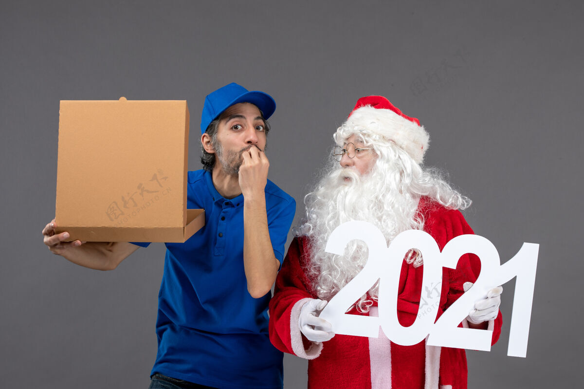 圣诞老人圣诞老人的正面图 男信使拿着食物盒 站在灰色的墙上信使盒子人