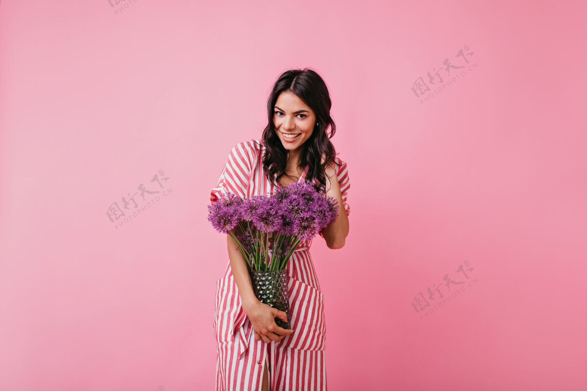 红色穿着时尚粉色迷笛裙的女孩看起来很友好 抱着满满的鲜花摆出室内肖像美丽可爱人