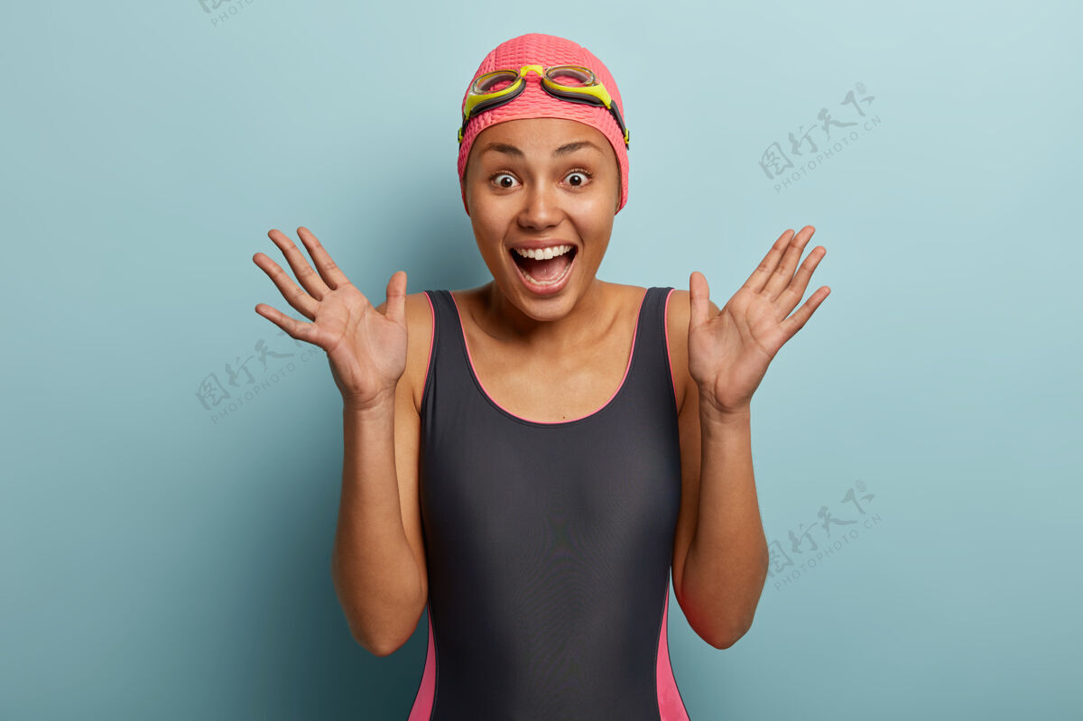游泳暴饮暴食的美籍黑人女子坦诚举手 有愉快反应 穿黑色泳衣女性护目镜运动