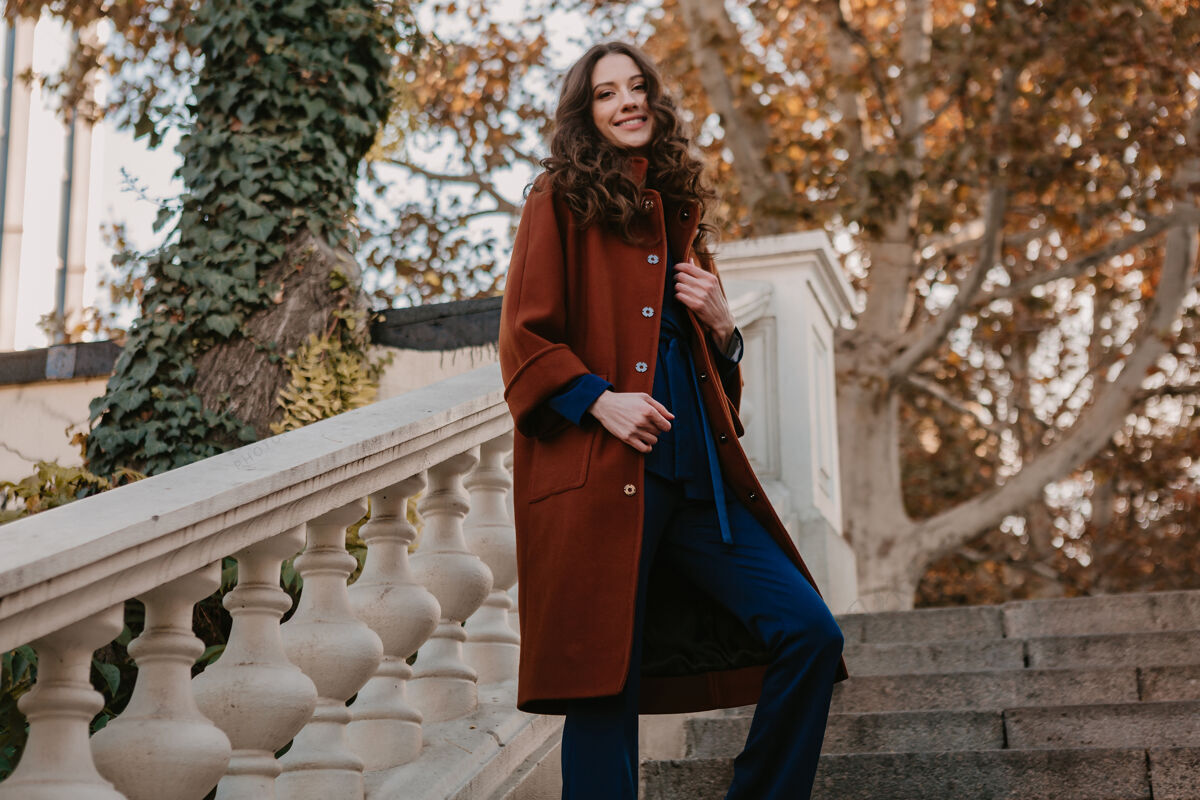 套装美丽时尚的微笑瘦身女子卷发走在街头楼梯上穿着温暖的棕色外套和蓝色西装 秋季时尚街头风女士套装女人