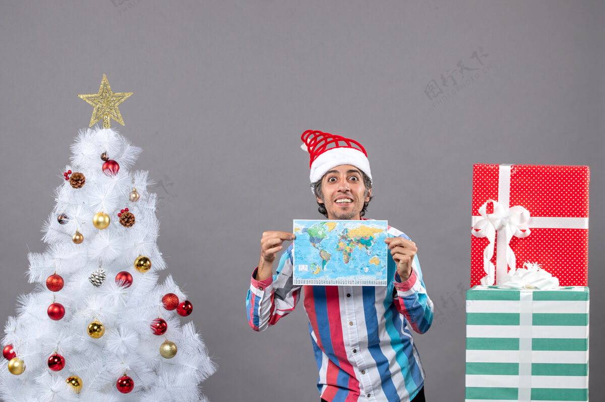 圣诞正面图满意的男子拿着螺旋弹簧圣诞帽双手拿着地图家伙手圣诞老人