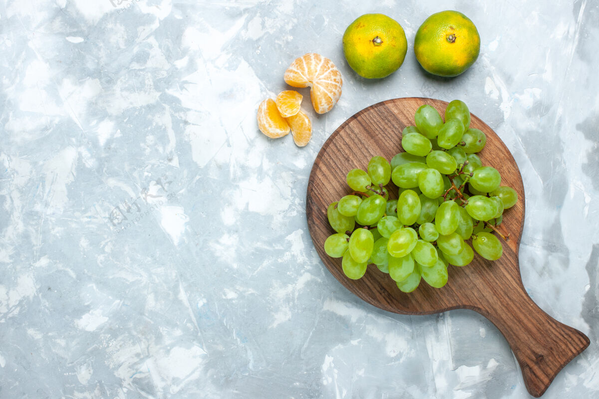 水果顶视图新鲜的绿色葡萄 醇厚多汁的水果和橘子放在灯桌上水果食品新鲜