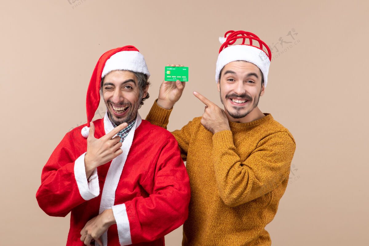 伙计们正面图两个快乐的家伙一个穿着圣诞老人的外套 另一个带着信用卡微笑的米色背景风景卡片外套