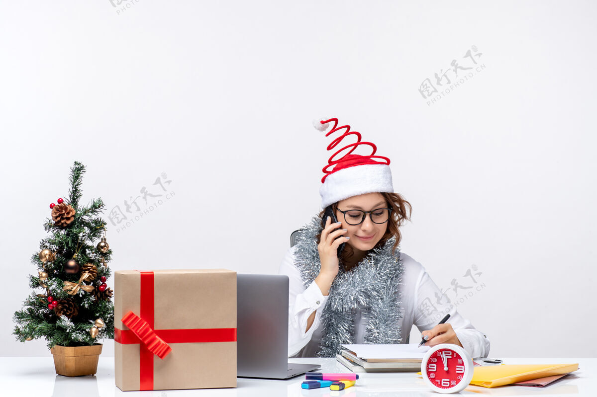 微笑正面图：假日工作的年轻女性在白色办公桌上打电话礼物年轻办公桌