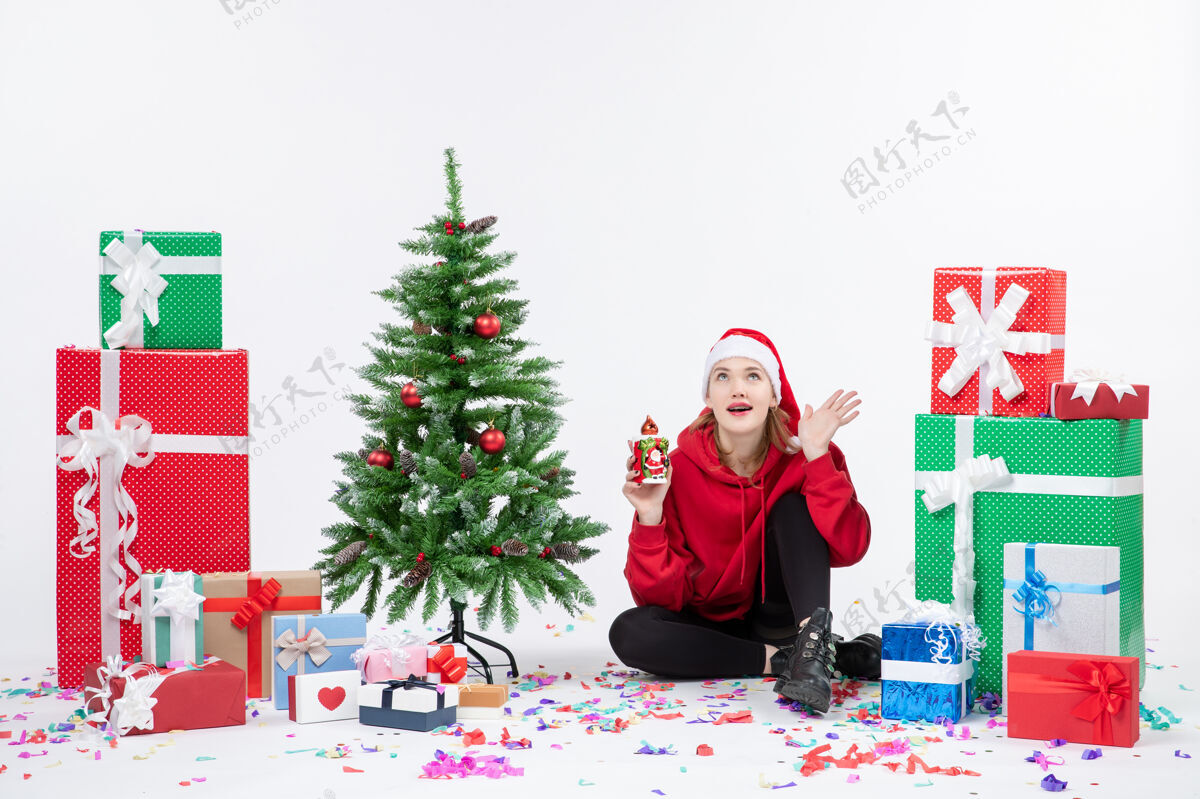 圣诞快乐前视图：年轻女子围坐在白色墙上拿着礼物快乐节日季节性的