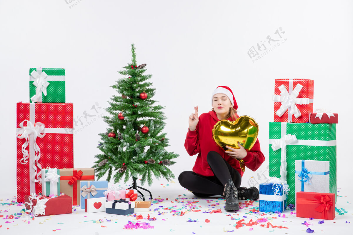 圣诞正面图：年轻女子围坐在白色墙壁上 手持金心形礼物快乐前面礼物