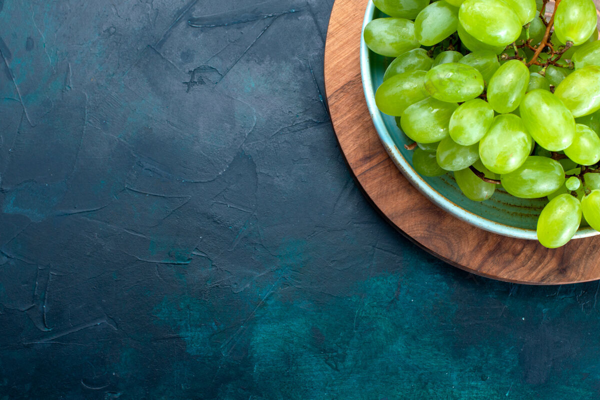 葡萄在深蓝色桌子上的盘子里 可以俯瞰新鲜的绿色葡萄 醇香多汁的水果顶部地面新鲜