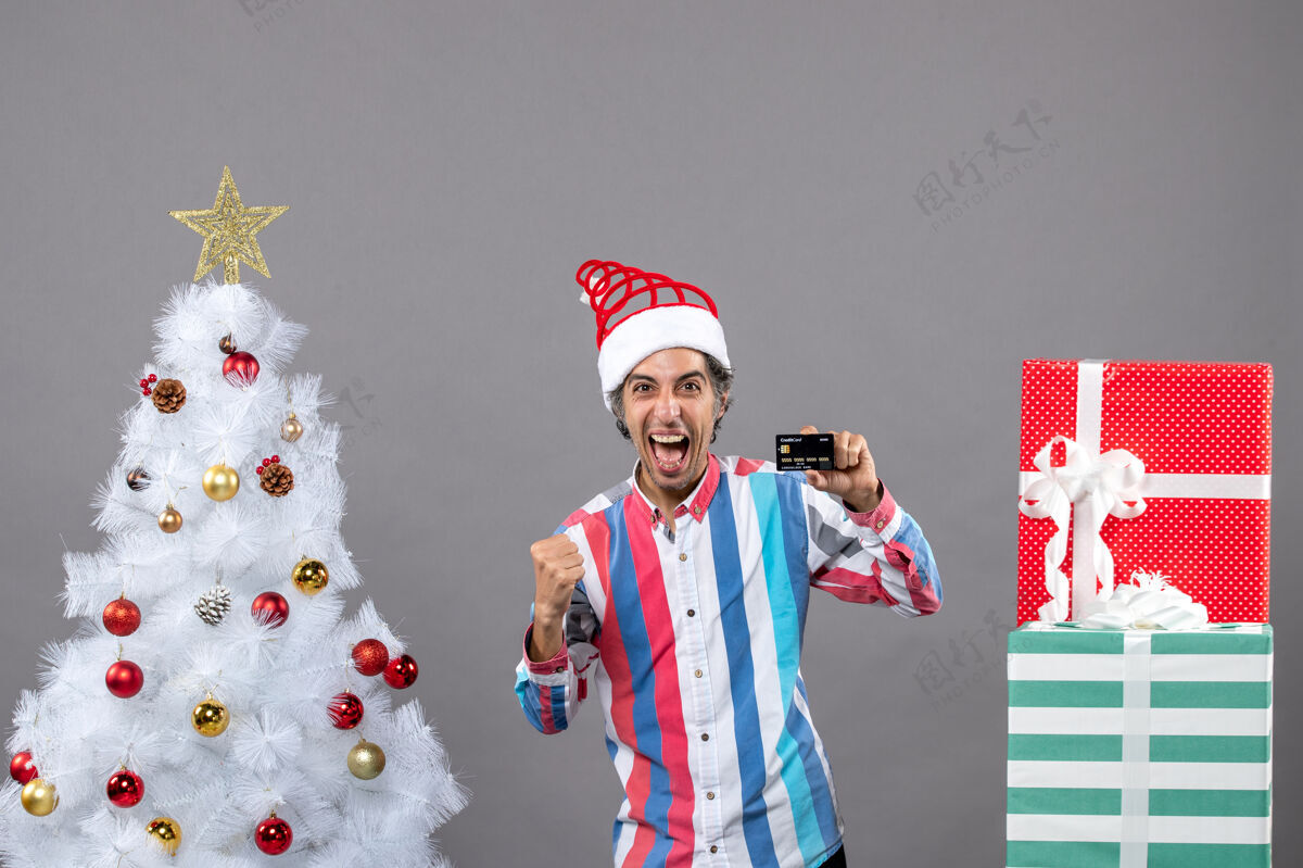 男正面图是一个喜出望外的人站在白色圣诞树旁胜利的姿态无辜站着喜出望外