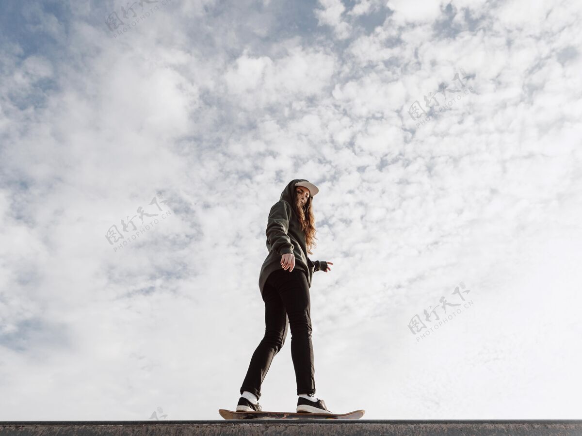 年轻玩滑板把戏的女人低头看滑板女孩户外运动
