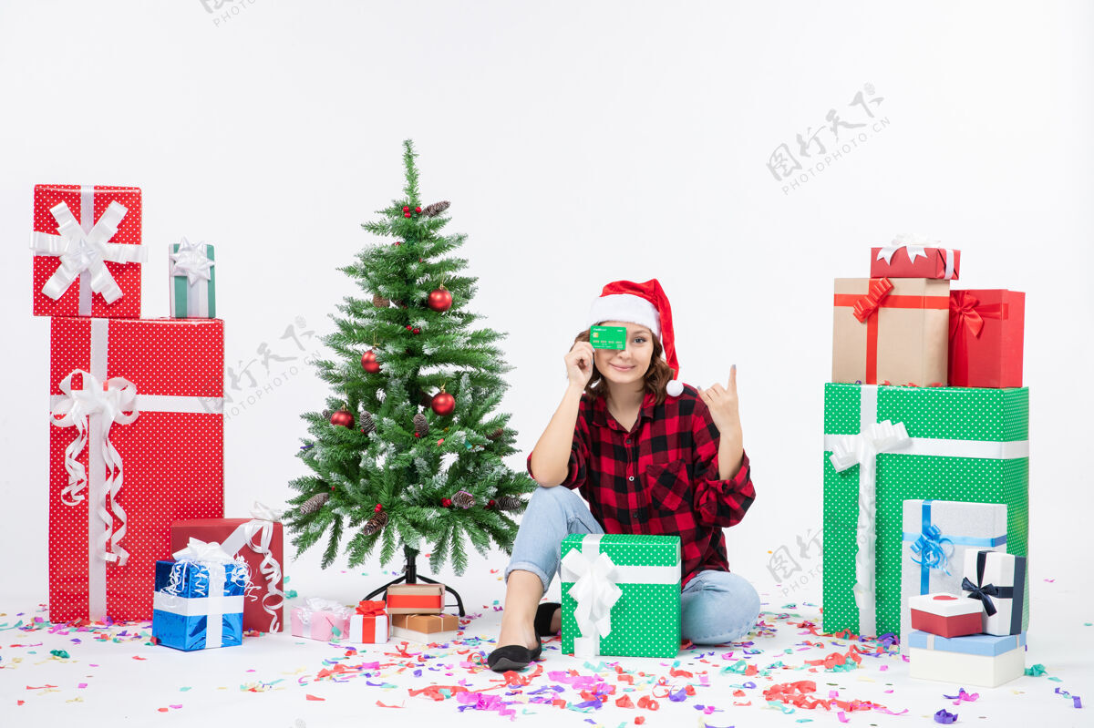 雪前视图年轻女子围坐在一个白色的墙上拿着绿色银行卡的礼物快乐情感圣诞快乐