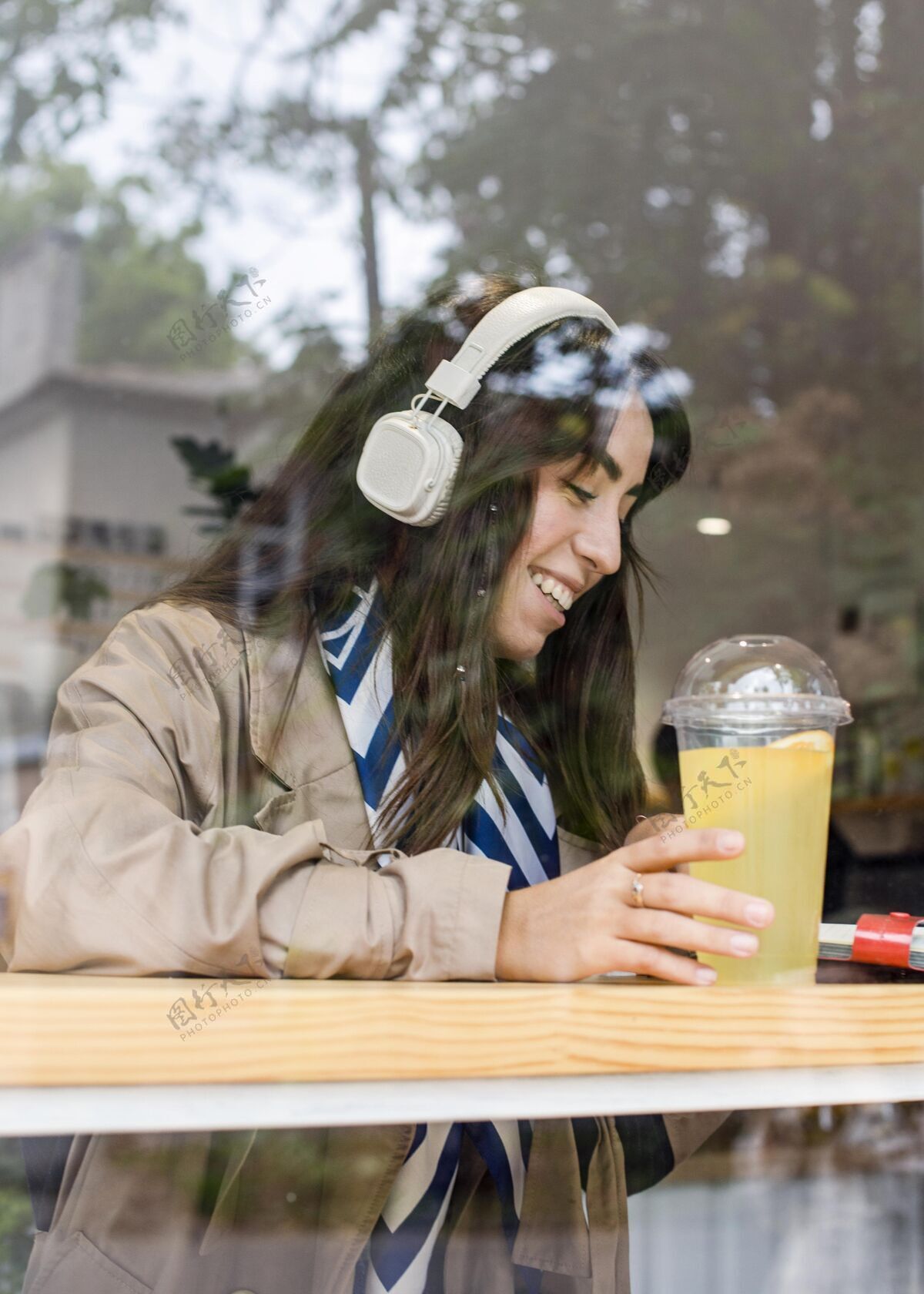 垂直咖啡厅里的女人带着新鲜的柠檬水和耳机热带健康异国情调