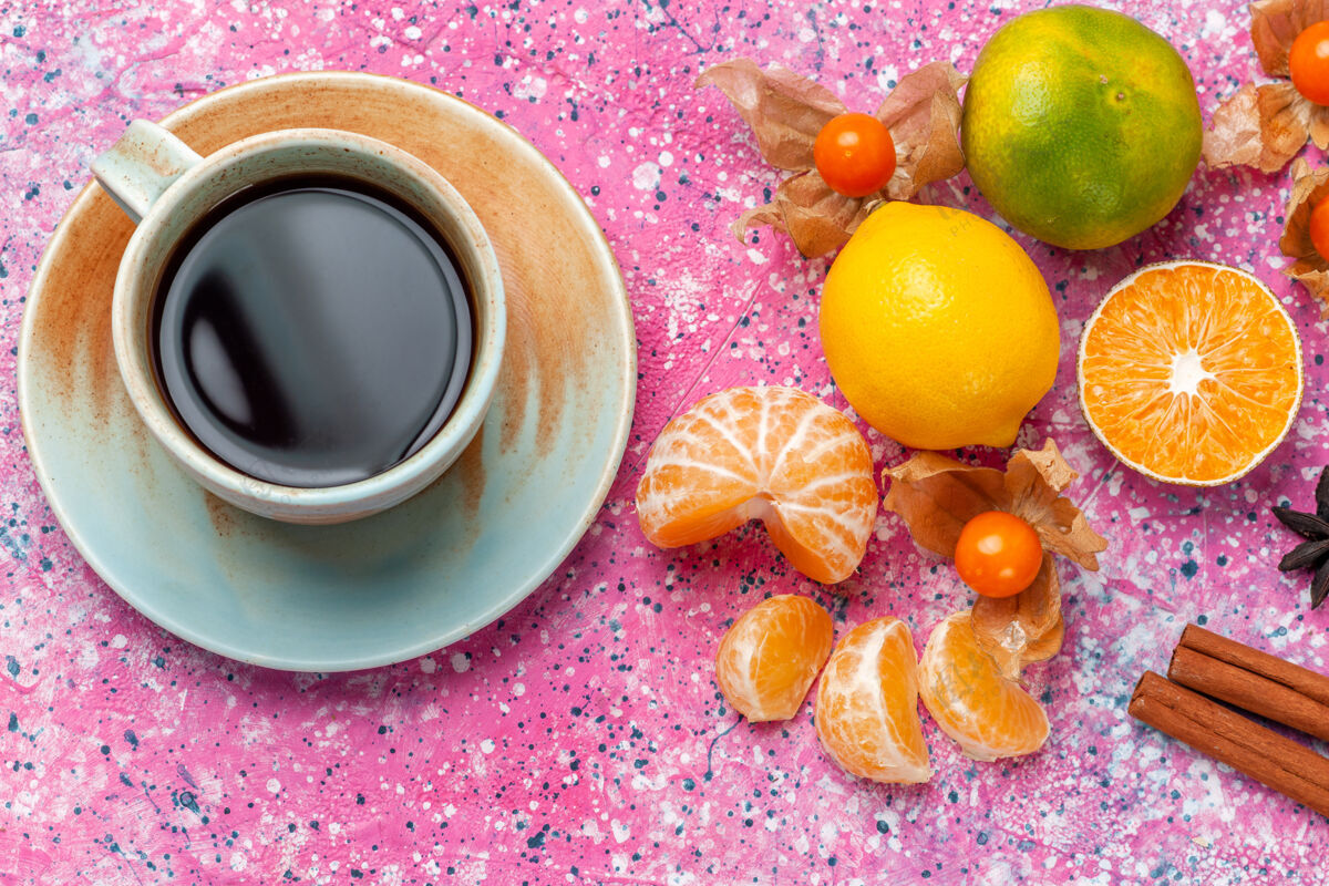 杯子在粉红色的背景上俯瞰新鲜的酸橘子和柠檬以及一杯茶橘子食物水果